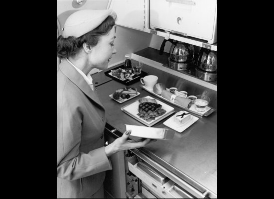 A United Airlines stewardess with food service in the galley in the late 1940s or early 1950s.
